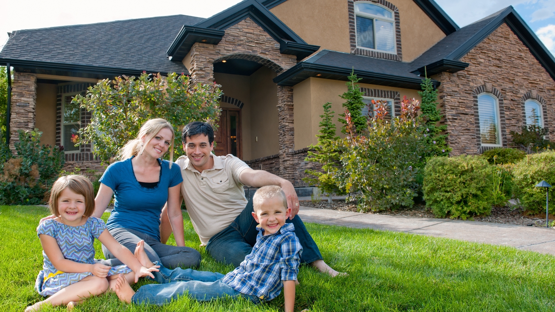 Smiling family on front lawn of a house